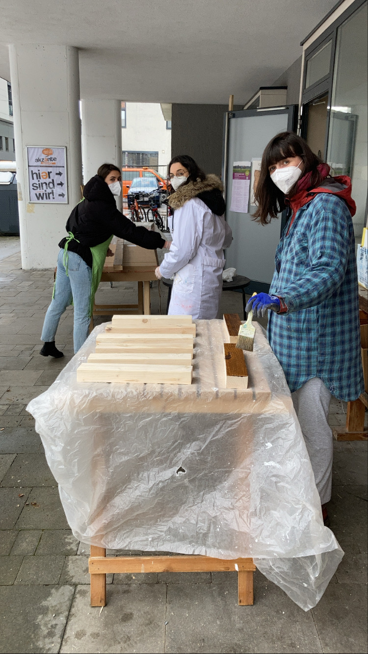 Drei Frauen arbeiten draußen an die Kisten, wo später die Bienen kommen werden