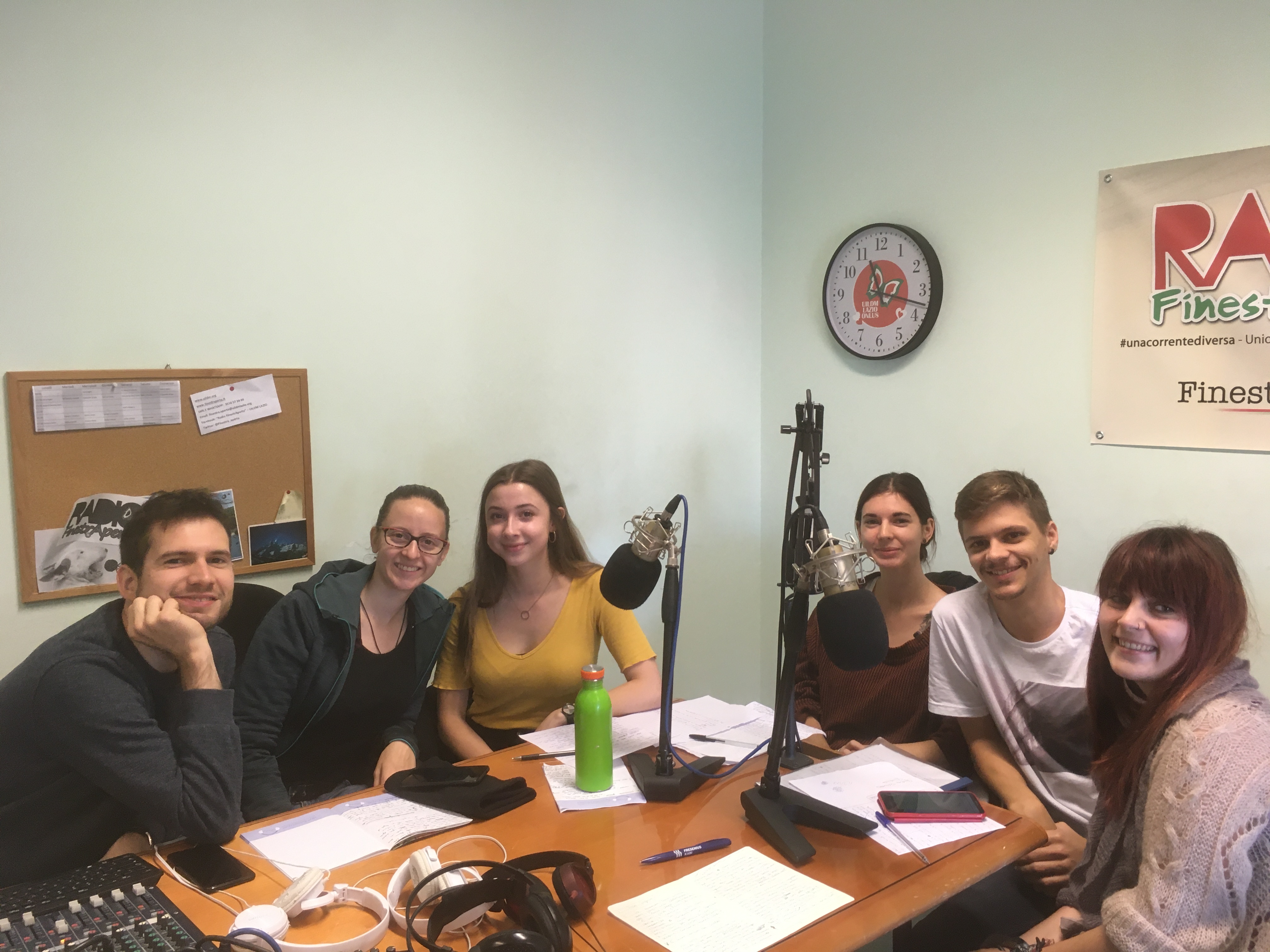 sechs junge Leute sitzen um einem Tisch und nehmen an einer Radiosendung Teil