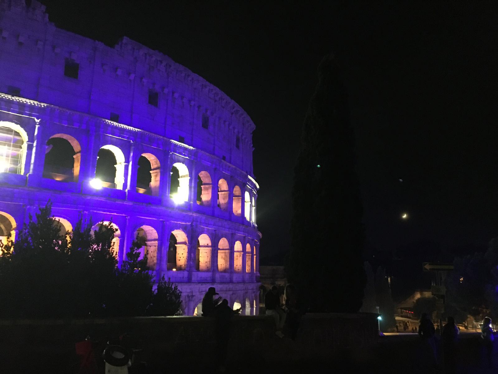 In der Nacht ist ein Lila beleuchteter Kolosseum zu sehen