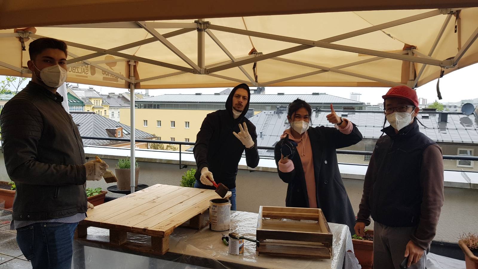 vier junge Leute lasieren Paletten und Beuten, Bienen-Aktion akzente Salzburg