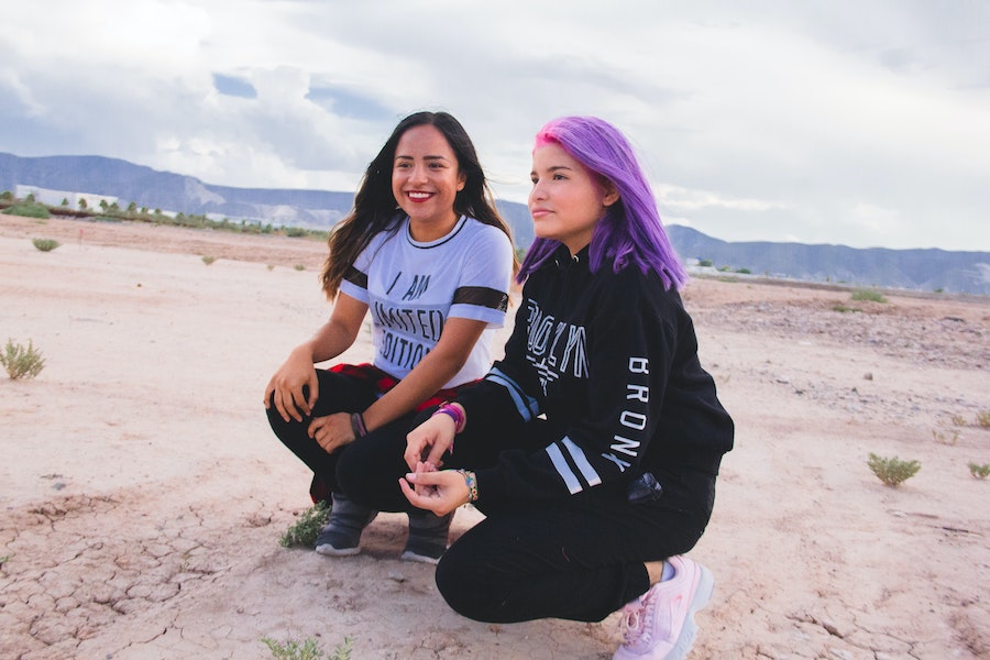 zwei Teenager-Mädchen hockelnd am Boden im Freien