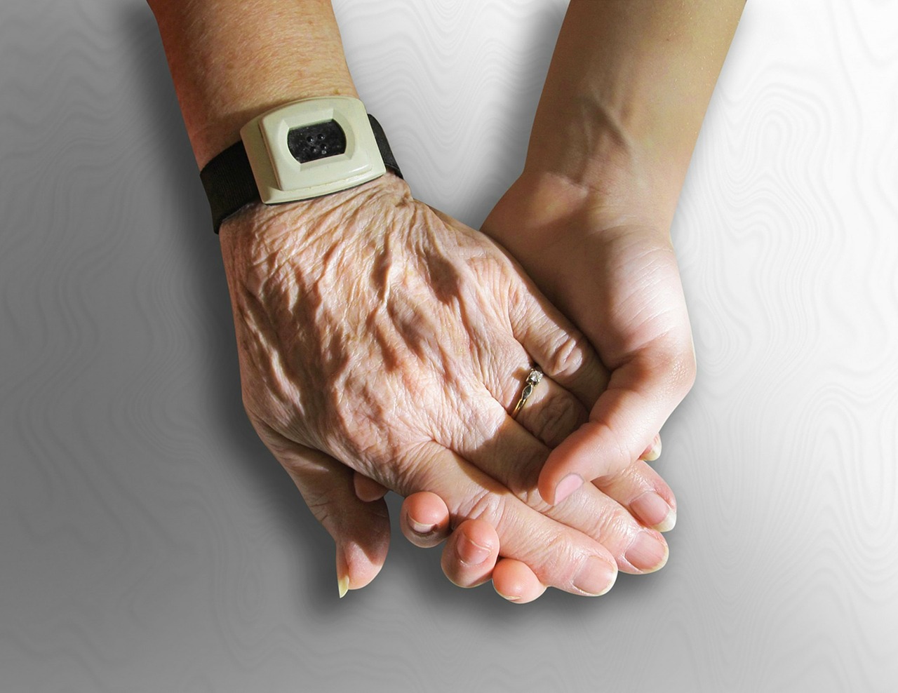 Hand einer älteren Person (Falten) in einer jungen Hand